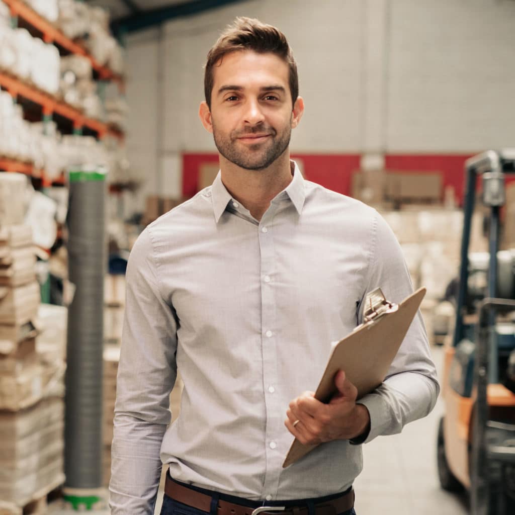 Manager standing in his warehouse with a clipboard
