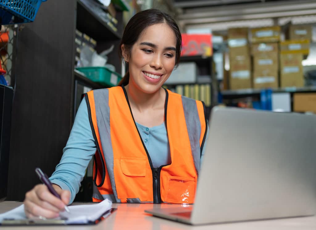 Female sitting and using laptop at warehouse factory